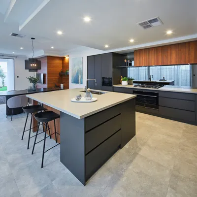 Open kitchen with a dark island, light island countertop, stools and wood-tone upper cabinets.