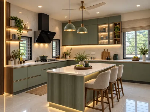 Green kitchen with a fluted island front, light counters, pale tile backsplash and brass-tone pendant lights.
