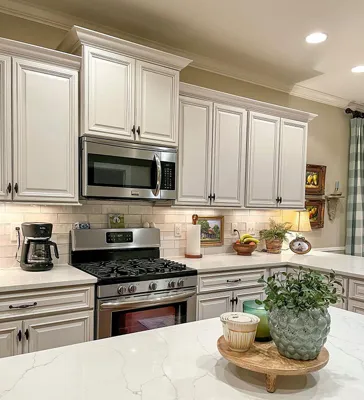 White raised-panel cabinetry, an over-range microwave, freestanding range and light counters.