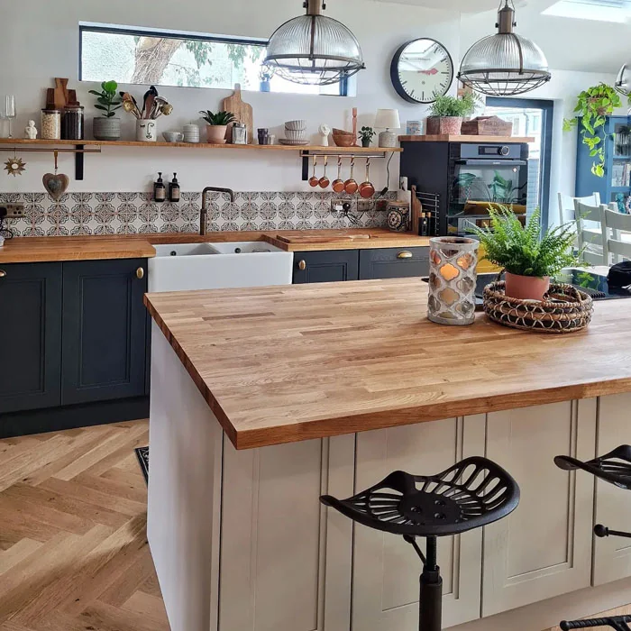 Kitchen with a wood-tone island top, dark lower cabinets, open shelving and hanging metal-shade lights.
